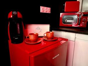 two coffee cups sitting on top of a red refrigerator at Redroom, Spa, Sauna, cheminée, romantique pour 2 in Quimperlé +19 photos