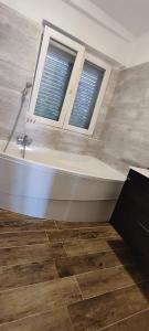 a bathroom with a bath tub and two windows at Apartmany Tisno Nikola in Tisno