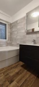 a bathroom with a tub and a sink and a mirror at Apartmany Tisno Nikola in Tisno