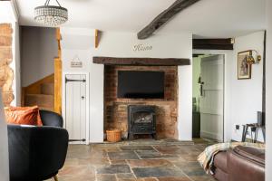 ein Wohnzimmer mit Kamin und Fernseher in der Unterkunft Castle Hill Cottage on a Scheduled Monument in Kenilworth