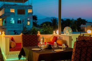 a table and chairs on a balcony with a view of a building at Lake Pichola Hibiscus Hotel in Udaipur
