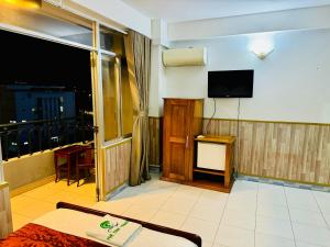 a hotel room with a television and a balcony at Tuệ Tĩnh Tower in Nha Trang