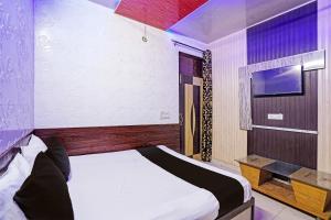 a bedroom with a bed and a tv on a wall at Hotel O Ginni in Rohtak