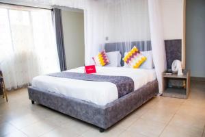 a bedroom with a large bed with yellow and orange pillows at Distinction Gardens in Siaya +38 photos