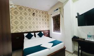 a bedroom with a large bed with blue and white pillows at FabHotel NRM Residency in Mysore
