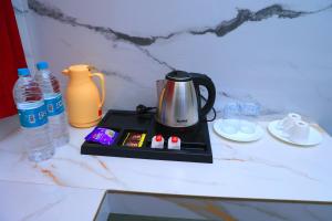 a tea kettle on a tray on a counter with water at RR Residency in Vishāram