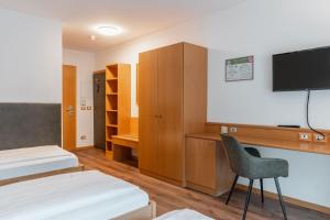 a room with two beds and a desk and a tv at Hotel Brenner - Stop & Go in Vipiteno