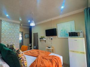 a room with a refrigerator and a bed with an orange blanket at Sintokha Guest House in Newcastle