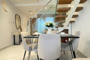 a dining room with a black table and white chairs at Elegant 2BR - Rooftop Luxe Skyline Escape in Abu Dhabi