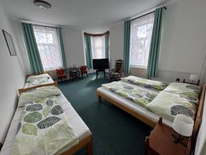 a bedroom with two beds and a tv in it at Hotel Praděd Rýmařov in Rýmařov