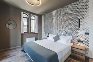 トリエステにある9 stanze - Boutique Roomsの大型ベッド付きのベッドルーム1室、模様のある壁