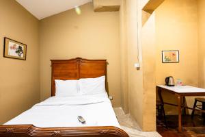 a bedroom with a bed and a table with a telephone at Rest Inn Yaowarat BKK in Samphanthawong