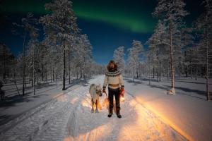 a woman walking a dog on a snow covered road at Lapland Aurora Riverside in Raiskio +57 photos