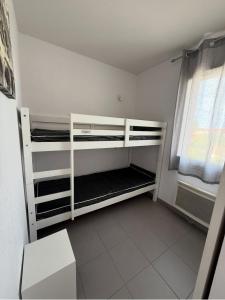 ein weißes Etagenbett in einem Zimmer mit Fenster in der Unterkunft T3 & tous conforts & piscine & sauna & plage in Argelès-sur-Mer