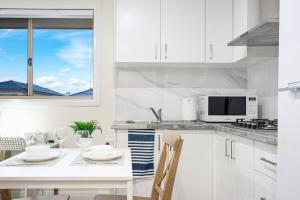 a white kitchen with a table and a microwave at Charming Studio in Tallawong in Riverstone