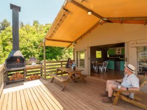 a man sitting on a deck with a fireplace at AfriCamps Magoebaskloof in Magoebaskloof +8 photos