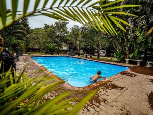 a man in a swimming pool in a resort at AfriCamps Hoedspruit in Hoedspruit