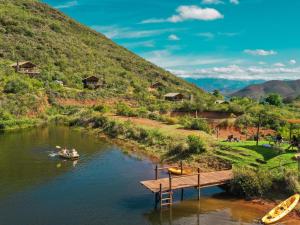 a boat on a river with a wooden bridge at AfriCamps at Pat Busch in Robertson