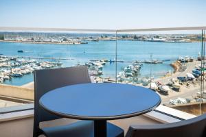 a table and chairs in a room with a view of a harbor at Jupiter Marina Hotel - Couples & Spa in Portimão