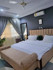 a bedroom with a large bed with a large white bedspread at UniGold Villa in Cape Coast