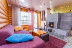 a living room with a purple couch and a fireplace at Koli Iso-Ryläys in Kolinkylä