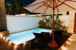 a swimming pool with a table and an umbrella at Slokayana Villas in Uluwatu