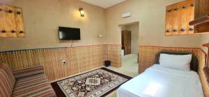Habitación con cama y TV en la pared. en نزل البستان Bustan lnn, en Nizwa