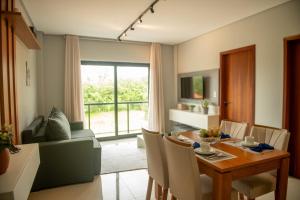 ein Wohnzimmer mit Tisch und ein Esszimmer in der Unterkunft Apto com 2 suites a 100m do Japaratinga Resort in São Bento