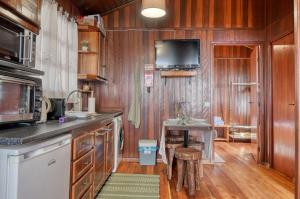 a kitchen with wooden cabinets and a tv on the wall at Chalet do Relógio d'Água, a Home in Madeira in Relógio do Poiso +23 photos