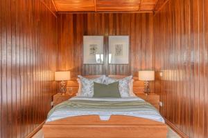 a bedroom with wooden walls and a bed with two lamps at Chalet do Relógio d'Água, a Home in Madeira in Relógio do Poiso