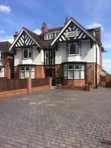 a white and black building on a brick street at Sutton Guest House in Birmingham