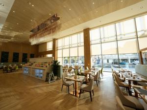 a restaurant with tables and chairs and large windows at Casa Diora Hotel Al Rawdah in Jeddah