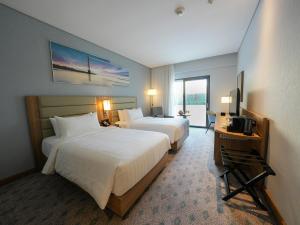a hotel room with two beds and a television at Casa Diora Hotel Al Rawdah in Jeddah
