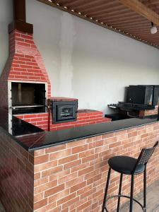 a brick counter with a brick oven and a stool at Espaço Carvalho in Itapecerica da Serra