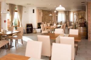 un restaurante con sillas y mesas blancas y mesa en Penzión u Vinára, en Veľký Krtíš
