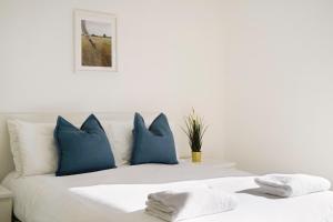 a white bed with blue pillows on top of it at New-Build 1-Bed Apartment in Luton in Luton