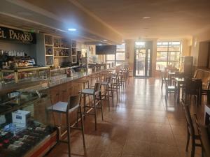 a bar in a restaurant with a row of stools at Hostal Restaurante el Paraíso in Don Benito