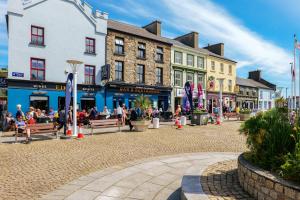 a street in a town with people sitting on benches at The Central House Clifden in Clifden