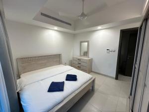 a bedroom with a bed with two blue pillows on it at Pinnacle Row Seaview Elegance in Muscat