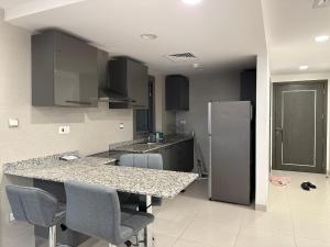 a kitchen with a counter with chairs and a refrigerator at Pinnacle Row Seaview Elegance in Muscat