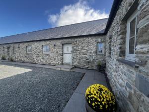 Un edificio de piedra con una puerta blanca y una bola amarilla. en Beudy Tanrallt, en Llanfachraeth