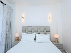 a bedroom with a large white bed with two lamps at Cosy 2 Bedroom at Ganjoni near the landmark site at Pembe za Ndovu - Elephant Task in Mombasa