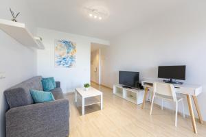 a living room with a couch and a desk with a tv at AlmeriaSuite Palm Beach in Almerimar