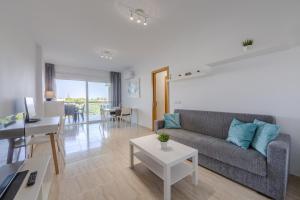 a living room with a couch and a table at AlmeriaSuite Palm Beach in Almerimar +15 photos