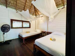 a room with two beds and a fan at Casa do Boi, charming house ideally located in Atins ! in Atins