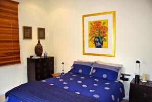 a bedroom with a blue bed and a painting on the wall at At Eleven - La Petite Maison in Sandy Bay