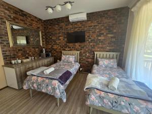 Un dormitorio con dos camas y una pared de ladrillo. en Villa Rosa Guest Farm, en Eersbewoond