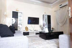 Una sala de estar blanca con un sofá y un televisor. en Logement entier appartement Mariste, en Hann