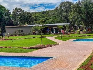 un jardín con una pasarela de ladrillo junto a una piscina en Villa Rosa Guest Farm, en Eersbewoond