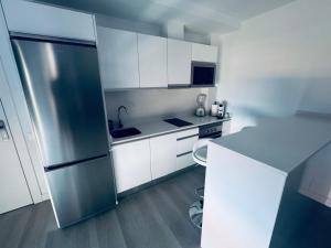 ArguineguínにあるModern Concept, Seaside Apartmentの白いキャビネットとステンレス製の冷蔵庫を備えたキッチン
